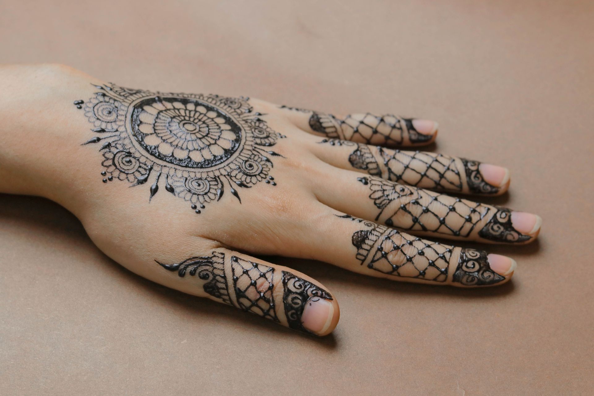 Close-up of a hand adorned with detailed henna tattoo, showcasing intricate patterns and elegance.